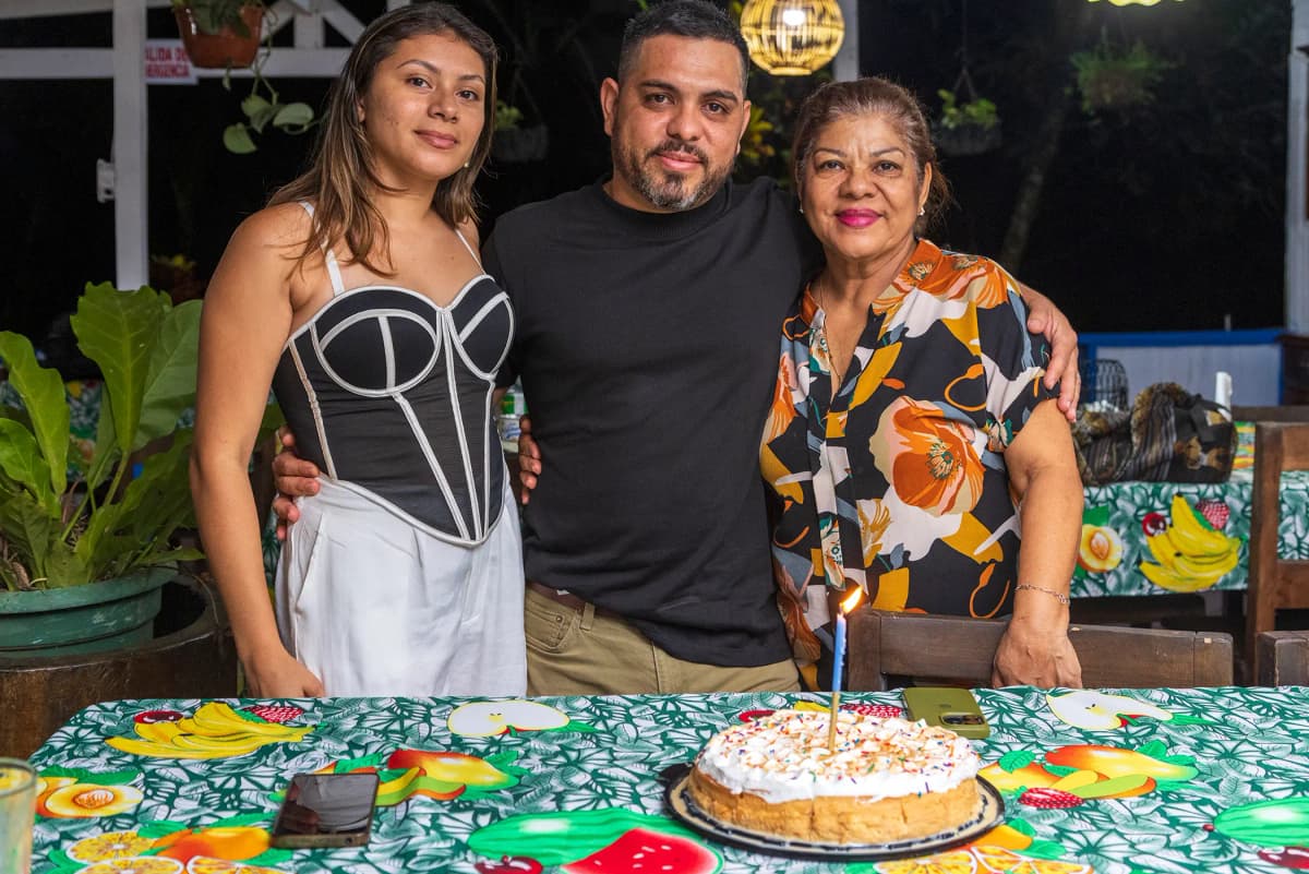 Family portrait of visitors smiling next to their birthday cake