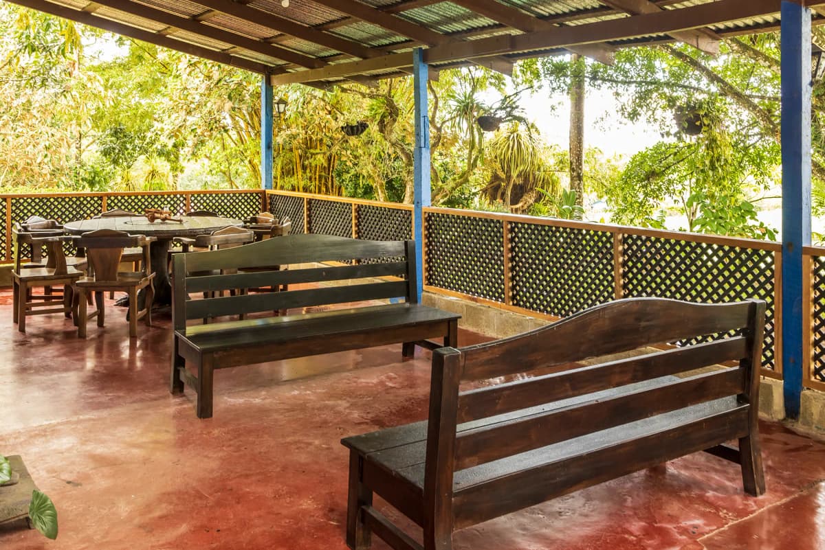 Outdoor hallway and terrace with rustic wooden benches and round dining table