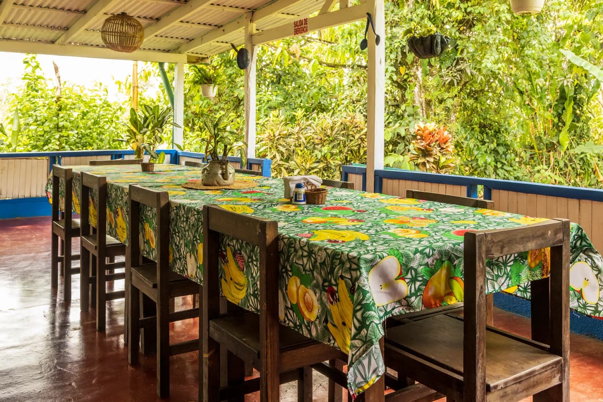 Long wooden dining table with fruit tablecloth on the restaurant terrace