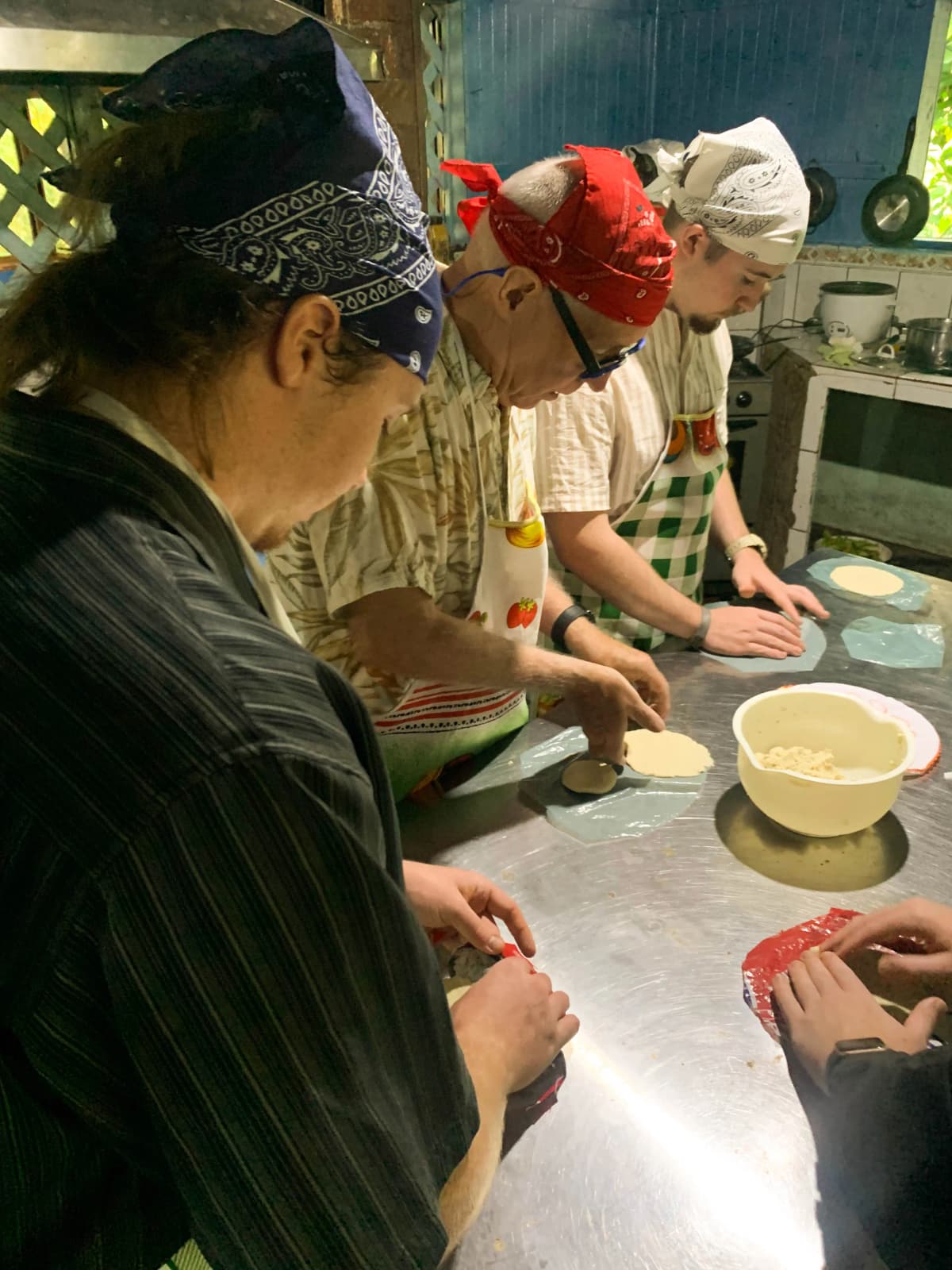 Tourists wearing aprons and bandanas pressing corn tortillas in the hands-on workshop