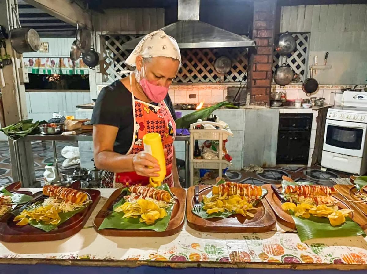 Tía Yami adding sauces to traditional Costa Rican tacos served on wooden boards