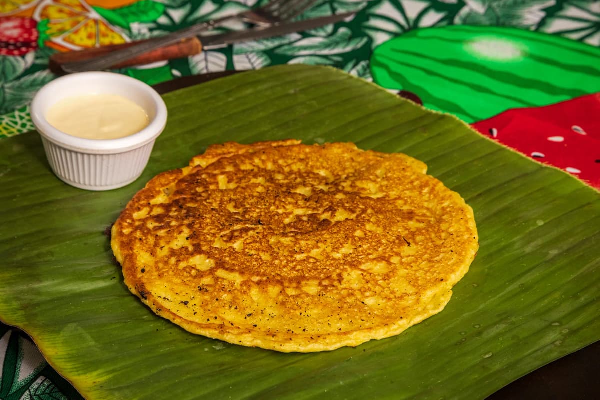 Traditional sweet corn chorreada served on a banana leaf with sour cream