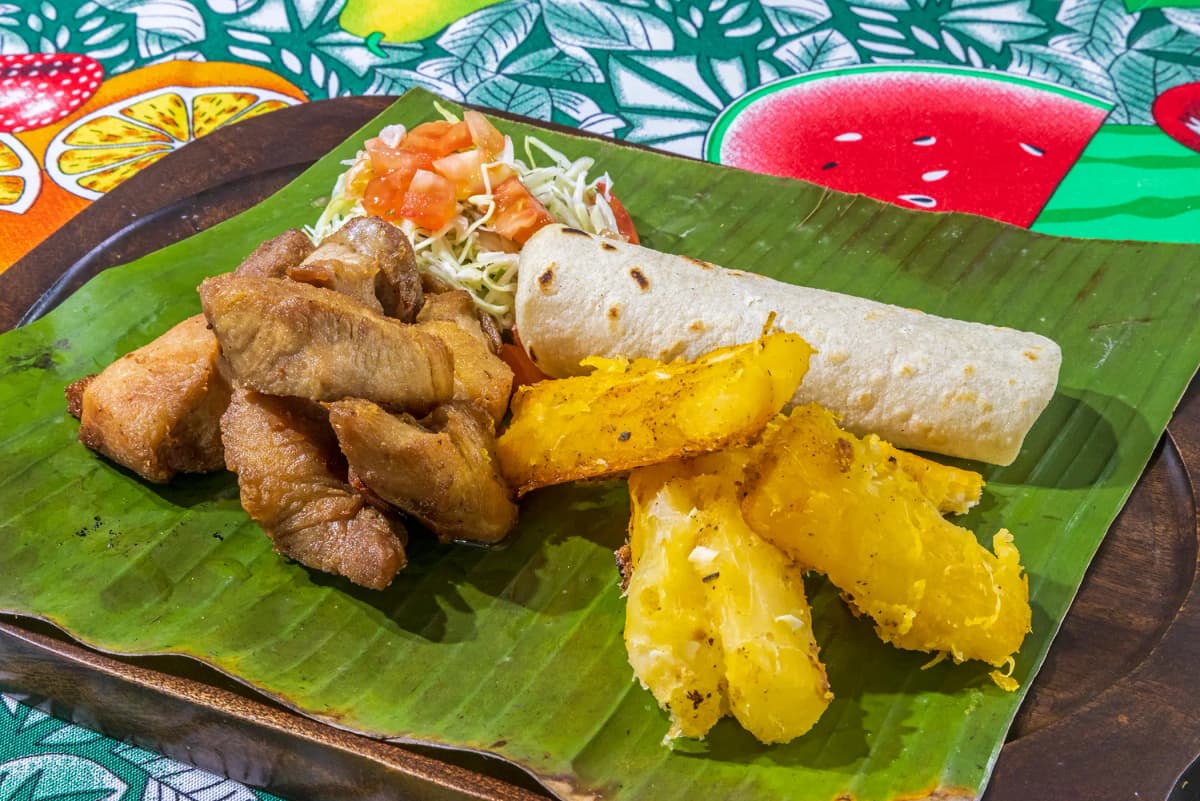Traditional pork chicharrón plate with fried cassava, fresh salad, and tortilla