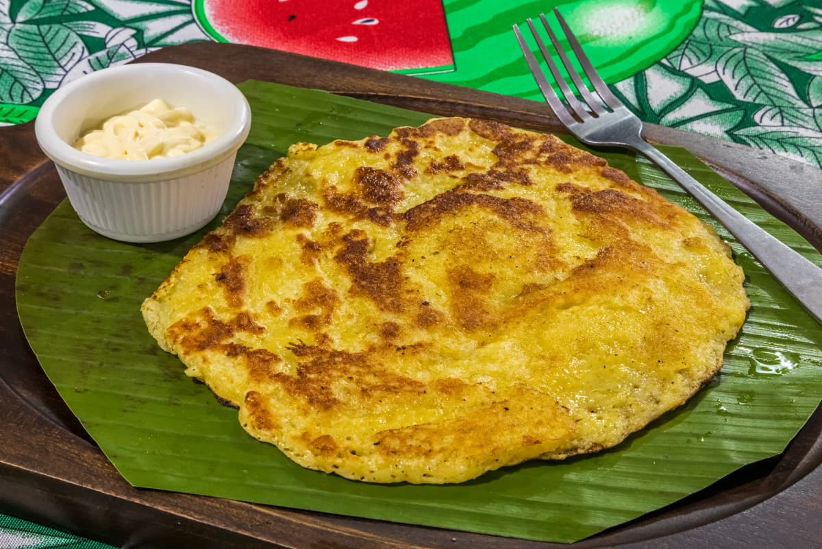 Wood-fired sweet corn chorreada with sour cream on a wooden plate