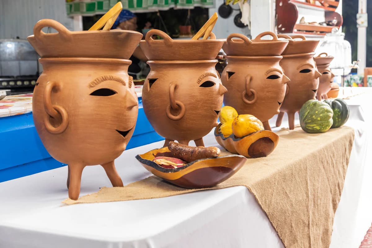 Handcrafted pots with carved face designs on the rustic buffet table